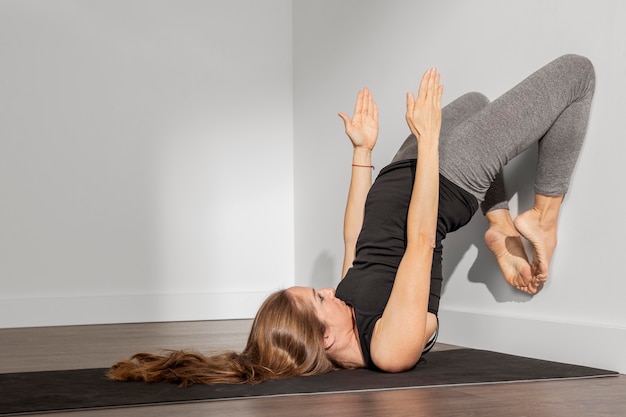 Donna adulta che fa yoga a casa