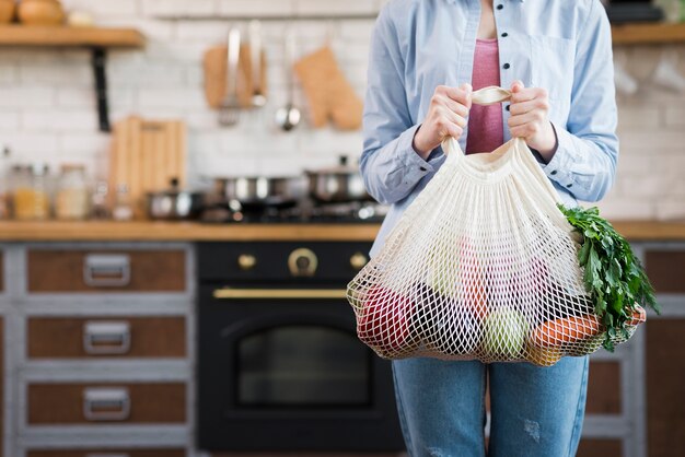 Adult woman holding reusable bag with organic vegetables