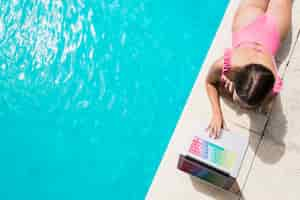 Foto gratuita donna adulta che utilizza computer portatile vicino alla piscina