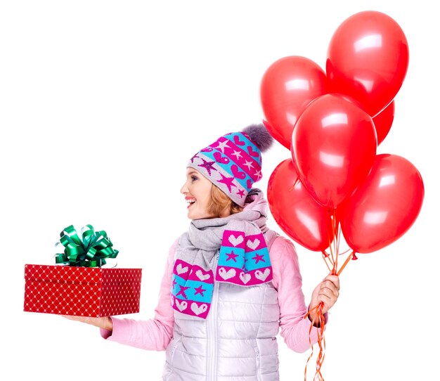 Adult woman with red gift box and balloons looking side isolated on white