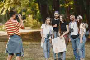 Foto gratuita concetto di avventura, escursione e persone. gruppo di amici sorridenti in una foresta. guy scatta una foto.