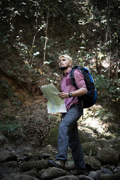 冒険の男は正しい道を見つけるために山道の地図を観察します。