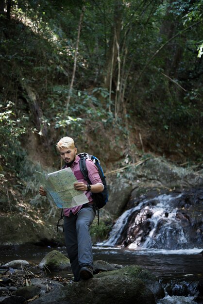 冒険の男は正しい道を見つけるために山道の地図を観察します。