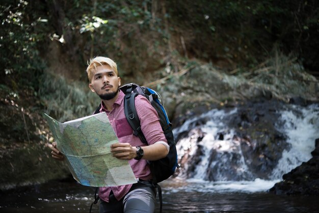 Free photo adventure man observing map on a mountain path  to find the the right way.