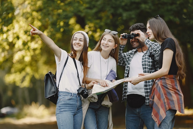 Foto gratuita avventura, viaggi, turismo, escursione e concetto di persone. gruppo di amici sorridenti in una foresta. uomo con il binocolo.