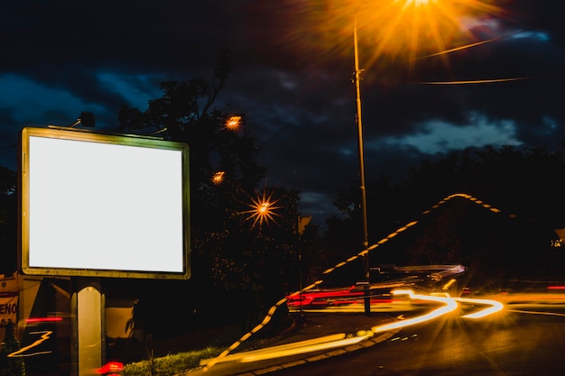 Advertisement billboard with blurred traffic lights at night