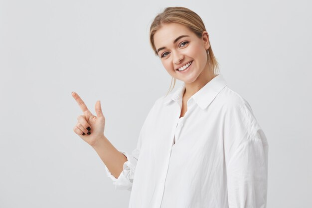 Advertising concept. Happy young woman with blonde hair wearing casual clothes, standing  with copy space for your information or promotional content