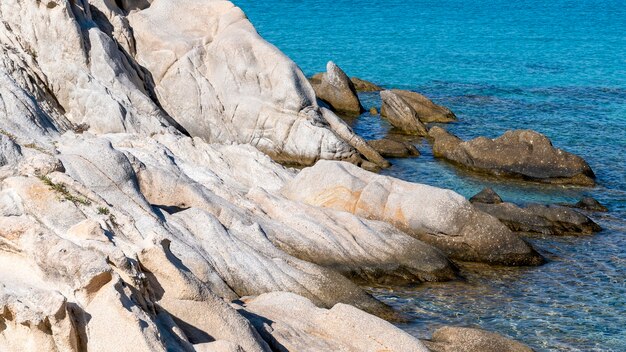 Aegean sea coast with rocks over the water, blue water, Greece