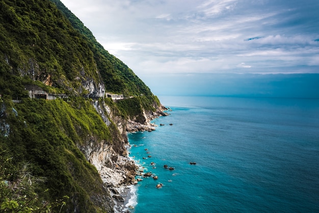 Foto gratuita bella ripresa aerea di scogliere boscose vicino a un oceano blu chiaro