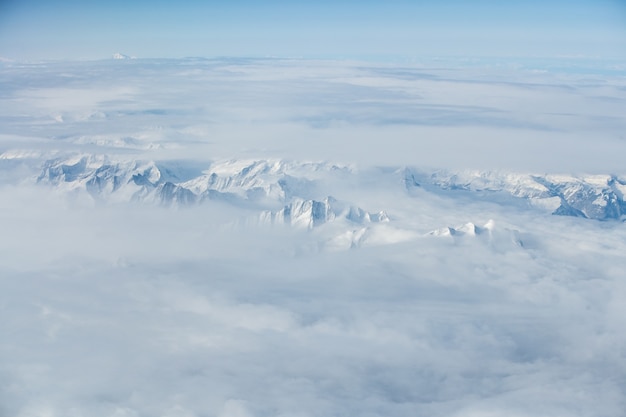 Ripresa aerea mozzafiato delle cime delle montagne innevate coperte di nuvole