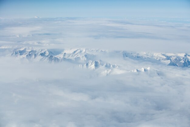 Aerial breathtaking shot of the snowy mountain tops covered in clouds