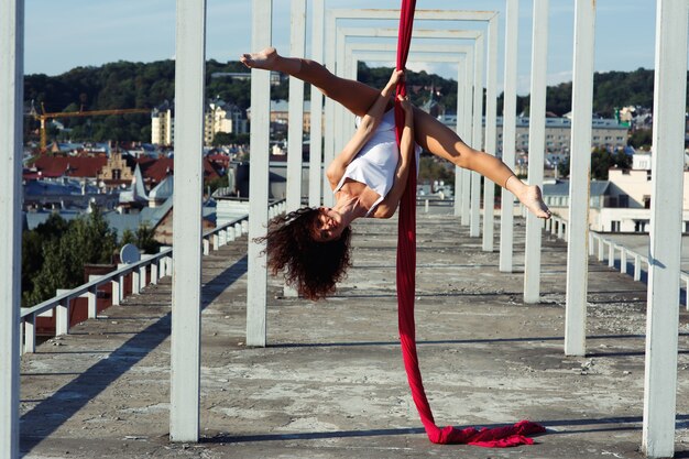 Aerial dance on rooftop, sexy brunette silk dancer in white dress