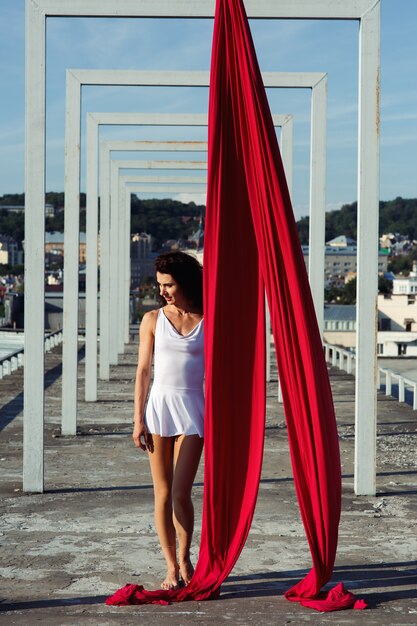 Aerial dance on rooftop, sexy brunette silk dancer in white dress