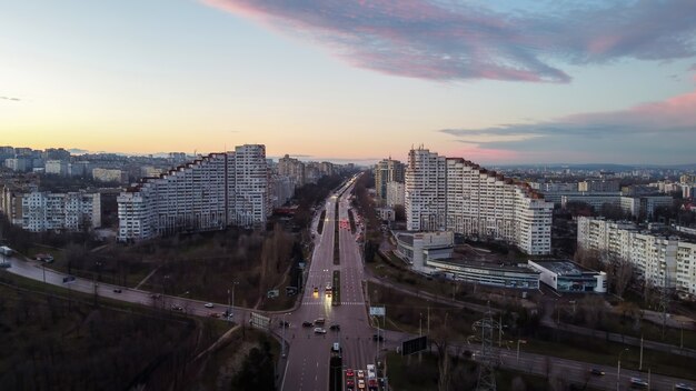Вид с воздуха на беспилотник Кишинева, Молдова в сумерках. Дорога с автомобилями и деревьями вдоль нее, ведущая к Городским воротам Кишинева.