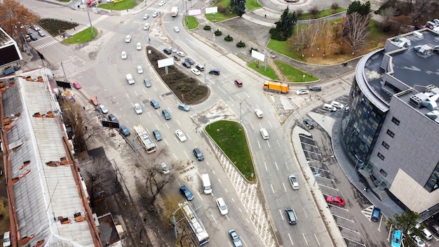 Aerial drone view of Chisinau, road with multiple moving cars, roundabout intersection, bare trees, top view