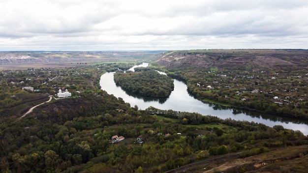 Foto gratuita vista aerea drone della natura in moldova, fiume galleggiante con cielo nuvoloso riflettente e villaggio vicino, colline con alberi