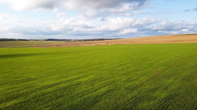 Aerial drone view of nature in Moldova, sown fields, trees in the distance, cloudy sky
