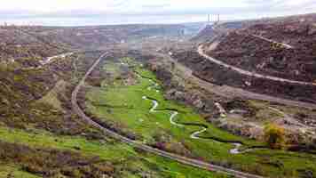 Foto gratuita vista aerea drone della natura in moldova, ruscello del torrente che scorre nel burrone, pendii con scarsa vegetazione e rocce, treno in movimento, cielo nuvoloso