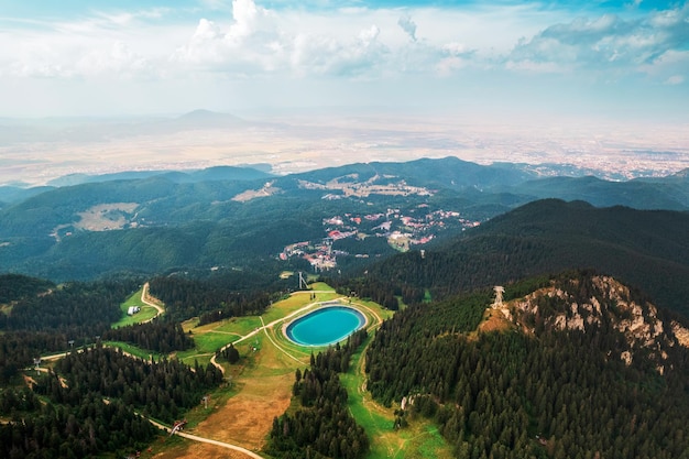 無料写真 遠くに緑豊かな森の町で覆われた山の頂上にあるポイアナ・ブラショフ・ルーマニア湖のドローン空撮