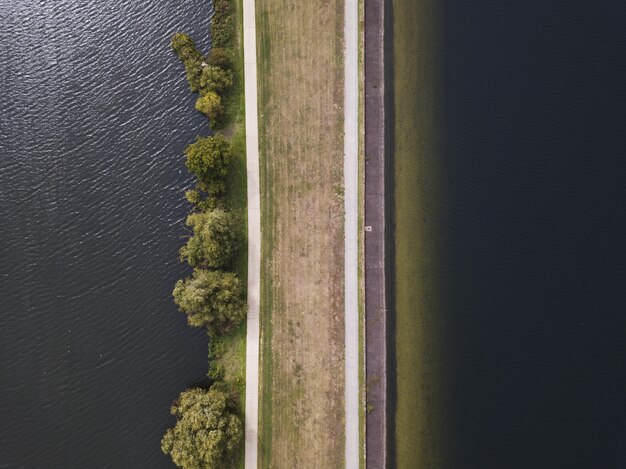 昼間の水域の近くの茶色の道路の空中ショット