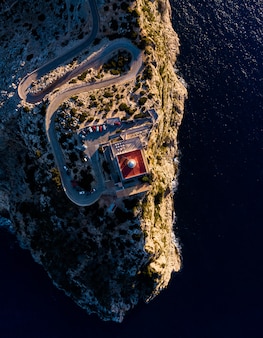 Aerial overhead shot of cliffs with a tower on top in the middle of the ocean