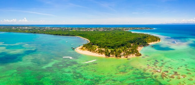 Aerial panoramic view of tropical island beautifully coned with lush trees under a clear sky
