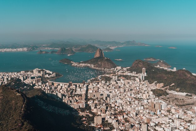 Aerial photo of Rio de Janeiro surrounded by hills and the sea under a blue sky in Brazil