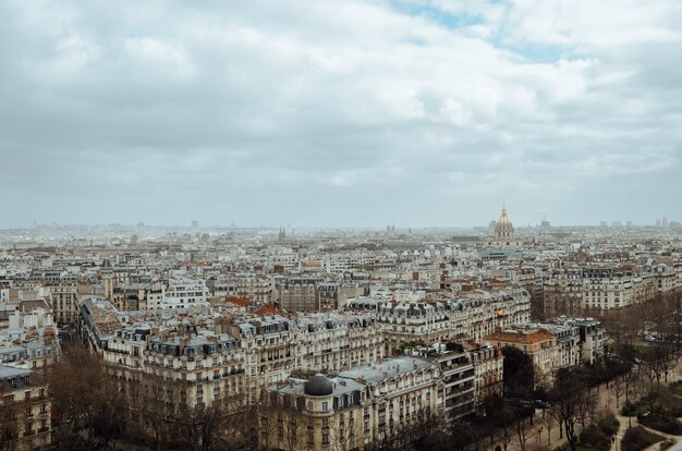 フランスの曇り空の下で緑と建物に覆われたパリの航空写真