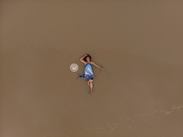 Ripresa aerea di una donna asiatica sdraiata su una spiaggia sabbiosa