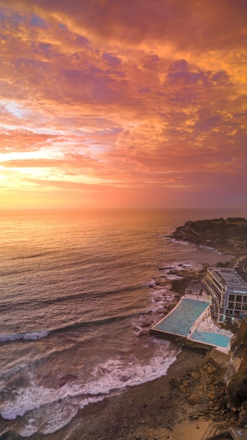 Foto gratuita ripresa aerea di una spiaggia con una grande piscina di un hotel e il mare durante il tramonto