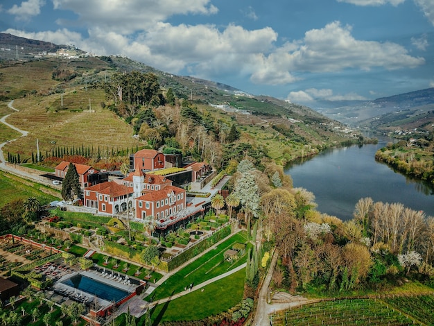 Aerial shot of a beautiful lake and a forest with a small residency in the middle