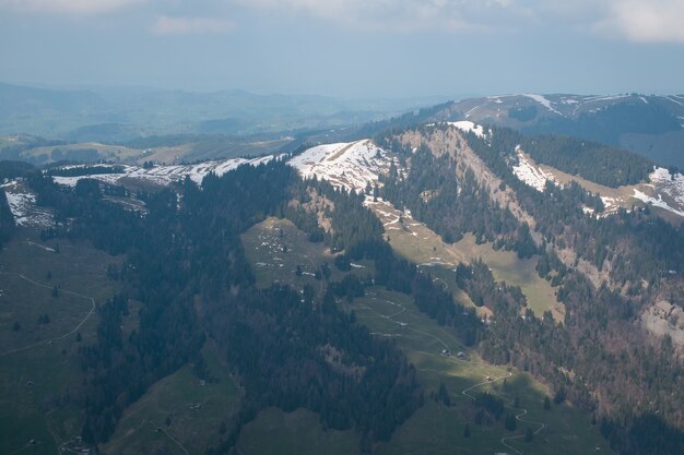 Aerial shot of a beautiful mountain range covered with snow under a cloudy sky