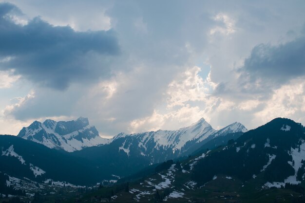 Aerial shot of a beautiful mountain range covered with snow under a cloudy sky