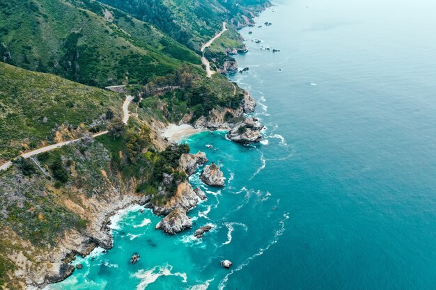 Aerial shot of the beautiful shoreline of the sea with rocks and greenery on the beach