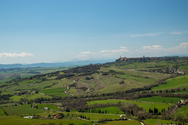 Aerial shot of the breathtaking grass-covered fields under the beautiful sky captured in Italy