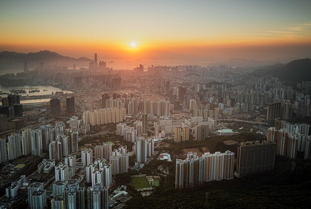 Aerial shot of city skyline under an orange sky at sunset