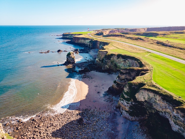 Aerial shot of a clear blue sea and a grassy shore