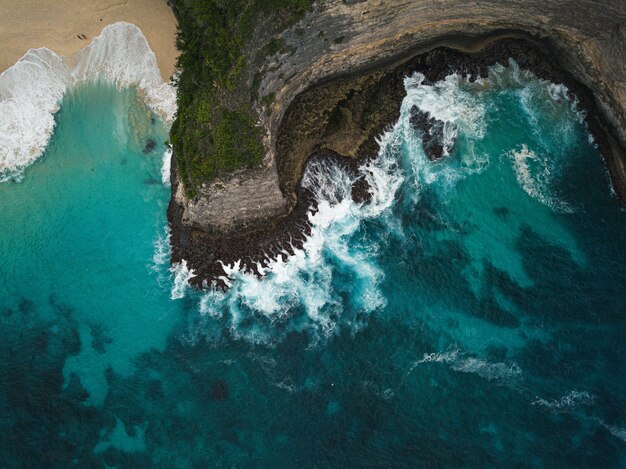 Aerial shot of the cliffs covered in greenery surrounded by the sea