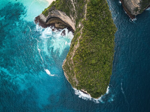 Aerial shot of the cliffs covered in greenery surrounded by the sea