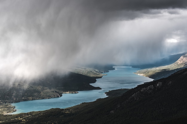 Free photo aerial shot of a forested mountain near a river under a foggy sky