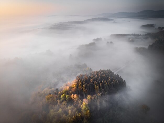 Воздушная съемка покрытой лесом горы, поросшей туманом, фоном великолепных форумов или блогом
