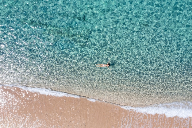 Aerial shot of a girl swimming in an amazing sea