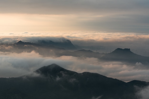Aerial shot of mountains under a cloudy sky at sunset