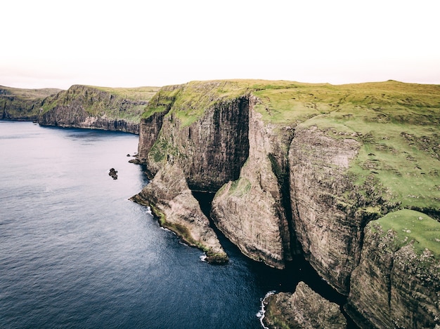 Free photo aerial shot of ocean and coast with huge cliffs and green field