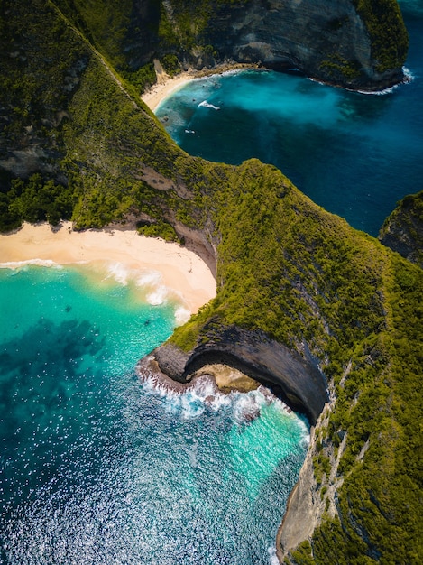 Aerial shot of the ocean  surrounded by beautiful cliffs covered in greens