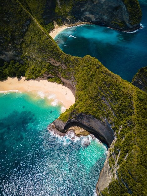 Aerial shot of the ocean  surrounded by beautiful cliffs covered in greens