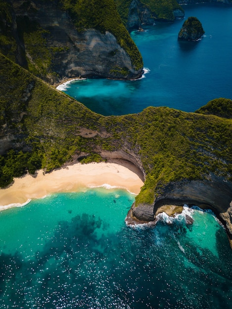 Aerial shot of the ocean  surrounded by beautiful cliffs covered in greens