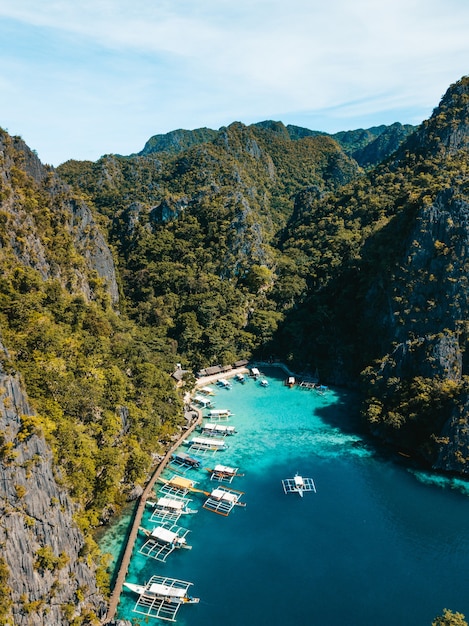 Aerial shot of the ocean  surrounded by beautiful mountains covered in greens