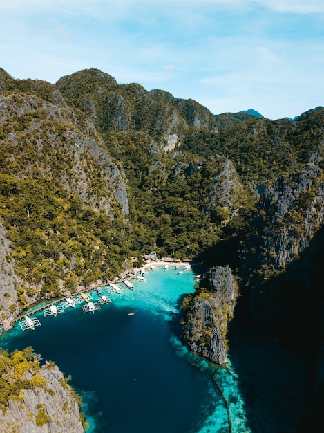 Aerial shot of the ocean  surrounded by beautiful mountains covered in greens