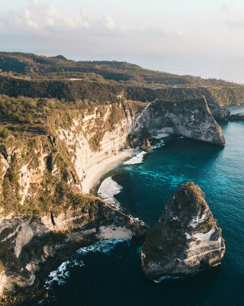 Aerial shot of the ocean surrounded by the high mountains covered in greens